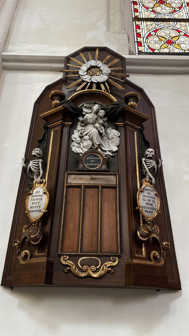 A carved wooden memorial with two skeletons on the church wall