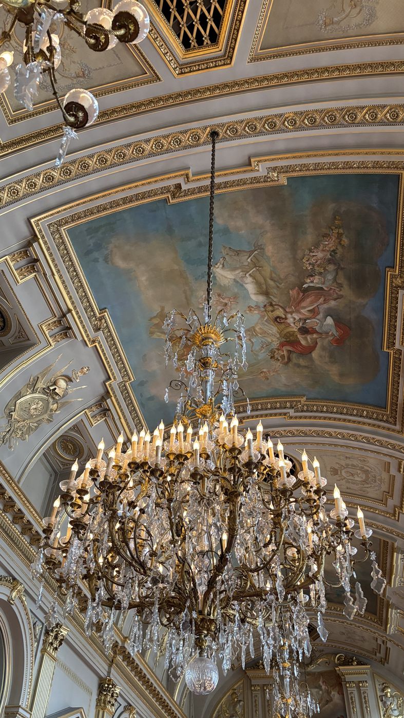 A crystal chandelier under a painted ceiling