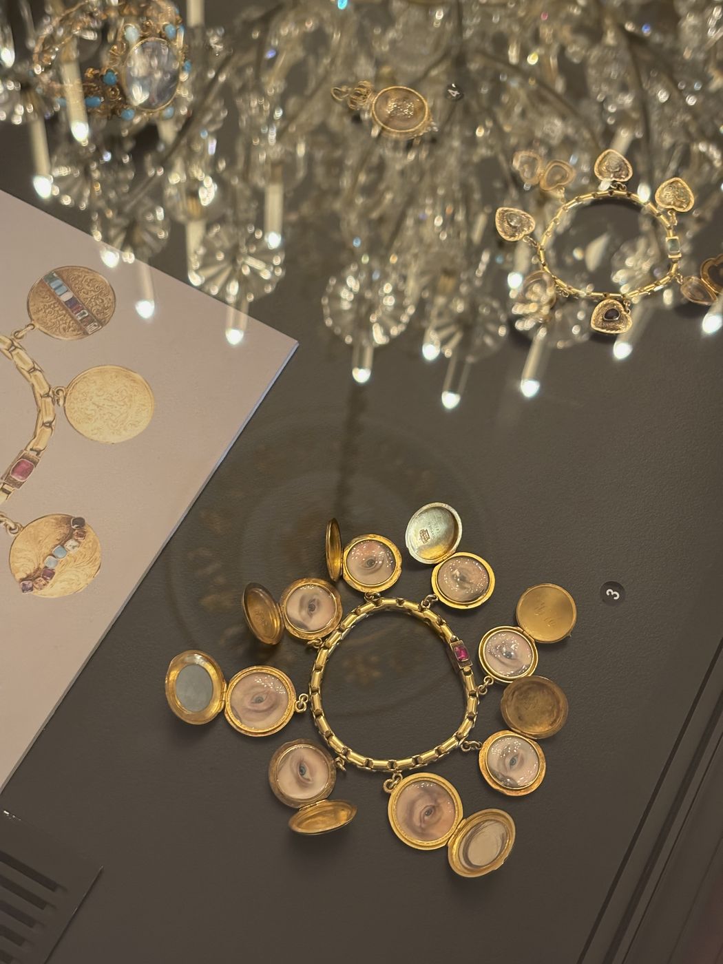 Gold medallions in a display case beneath a chandelier