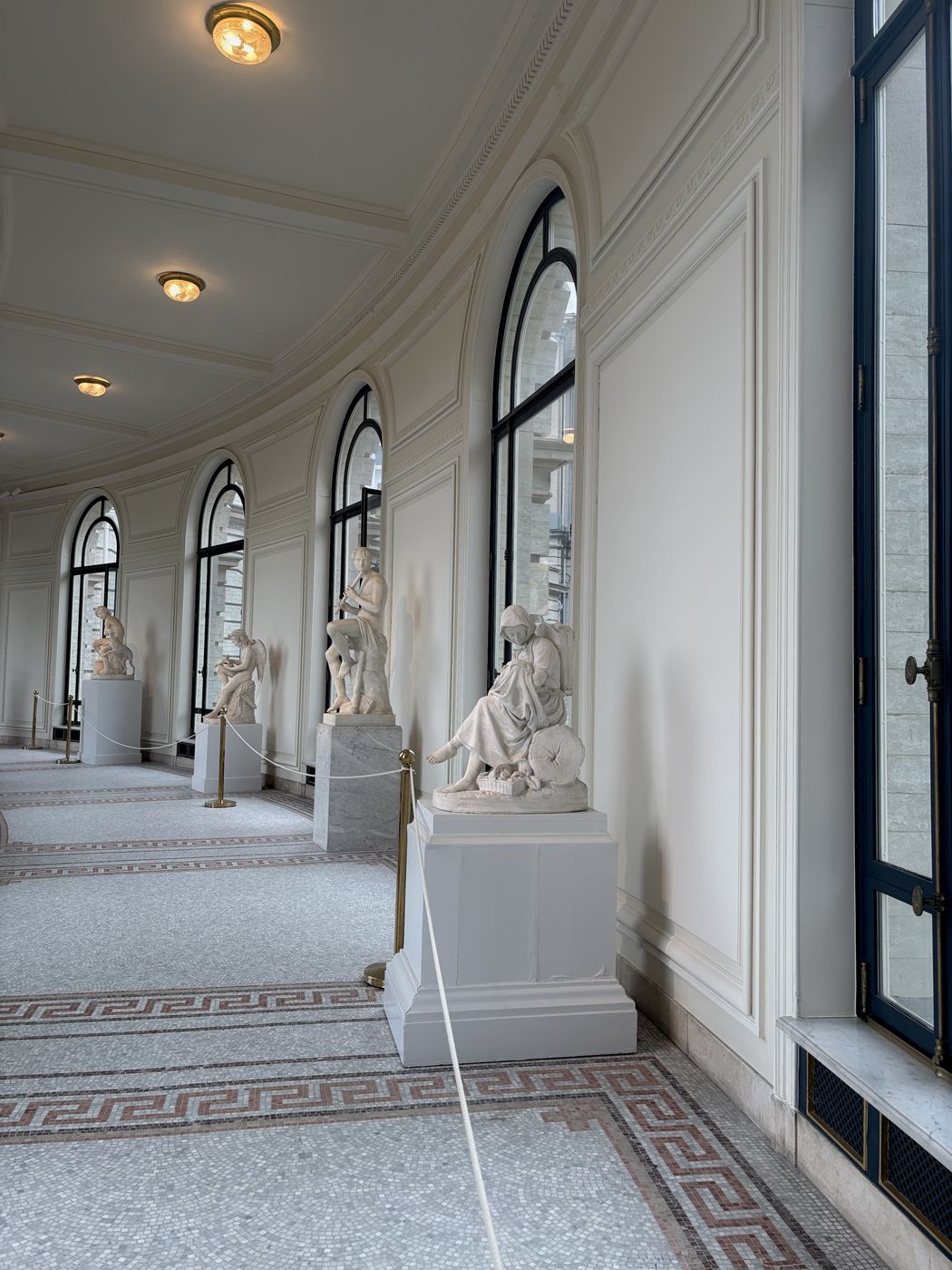 A long white gallery lined with marble sculptures