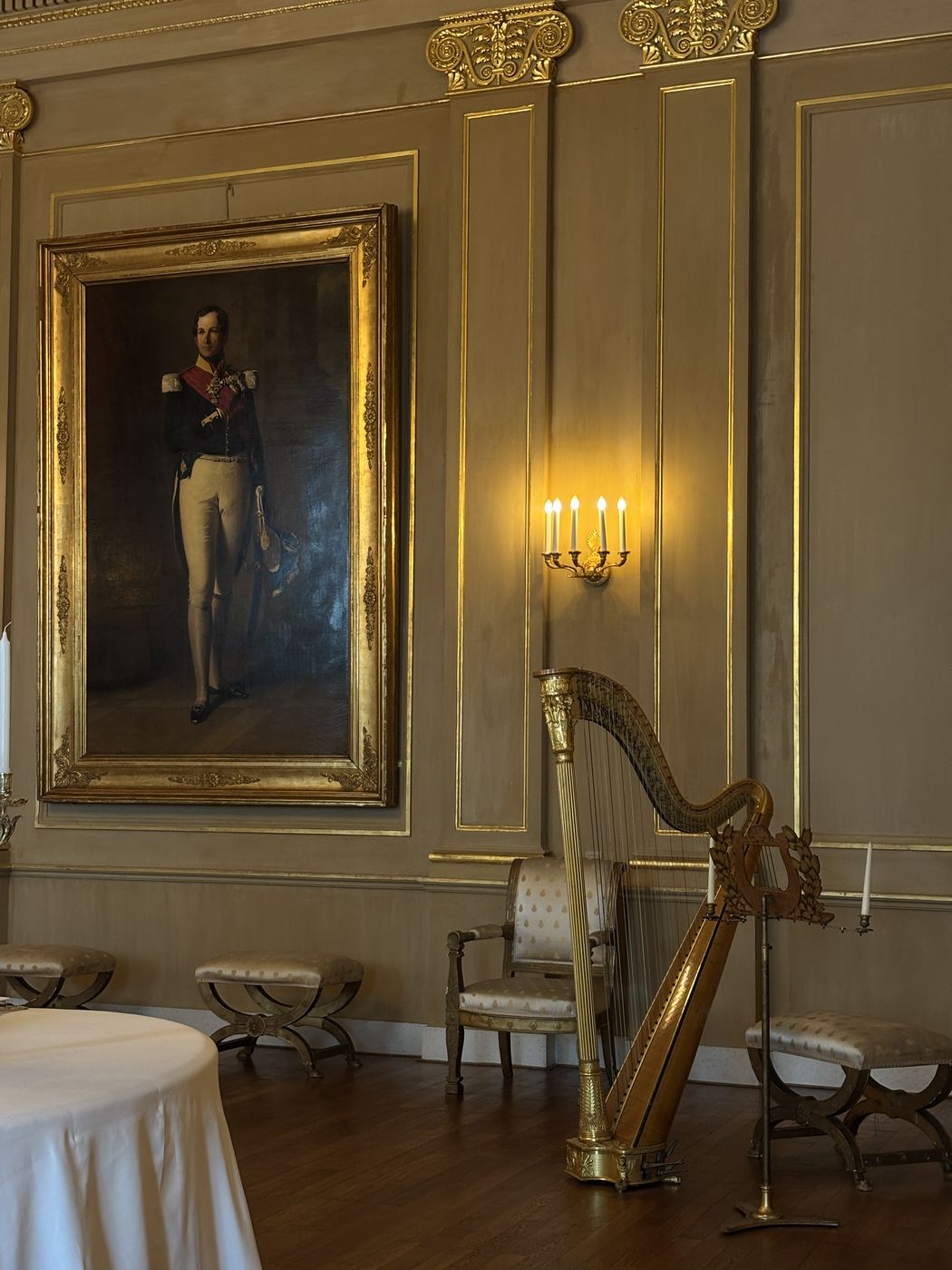 A gilded harp beneath a royal portrait