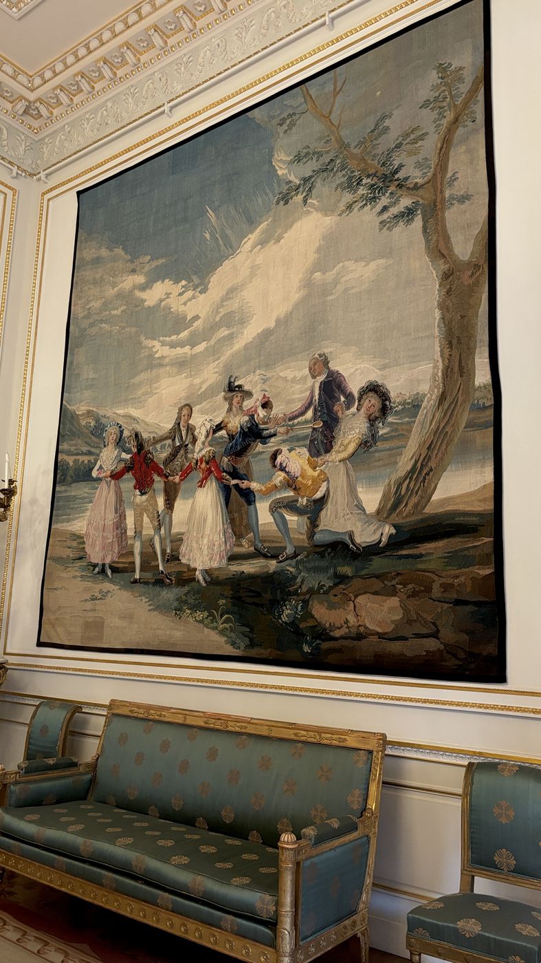 A large tapestry above a blue silk sofa