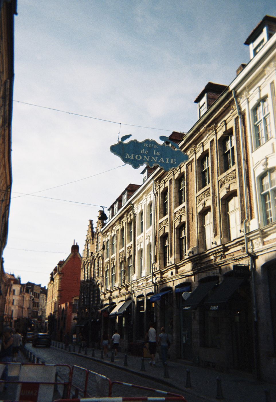 The Rue de la Monnaie street sign hanging over the street, on film