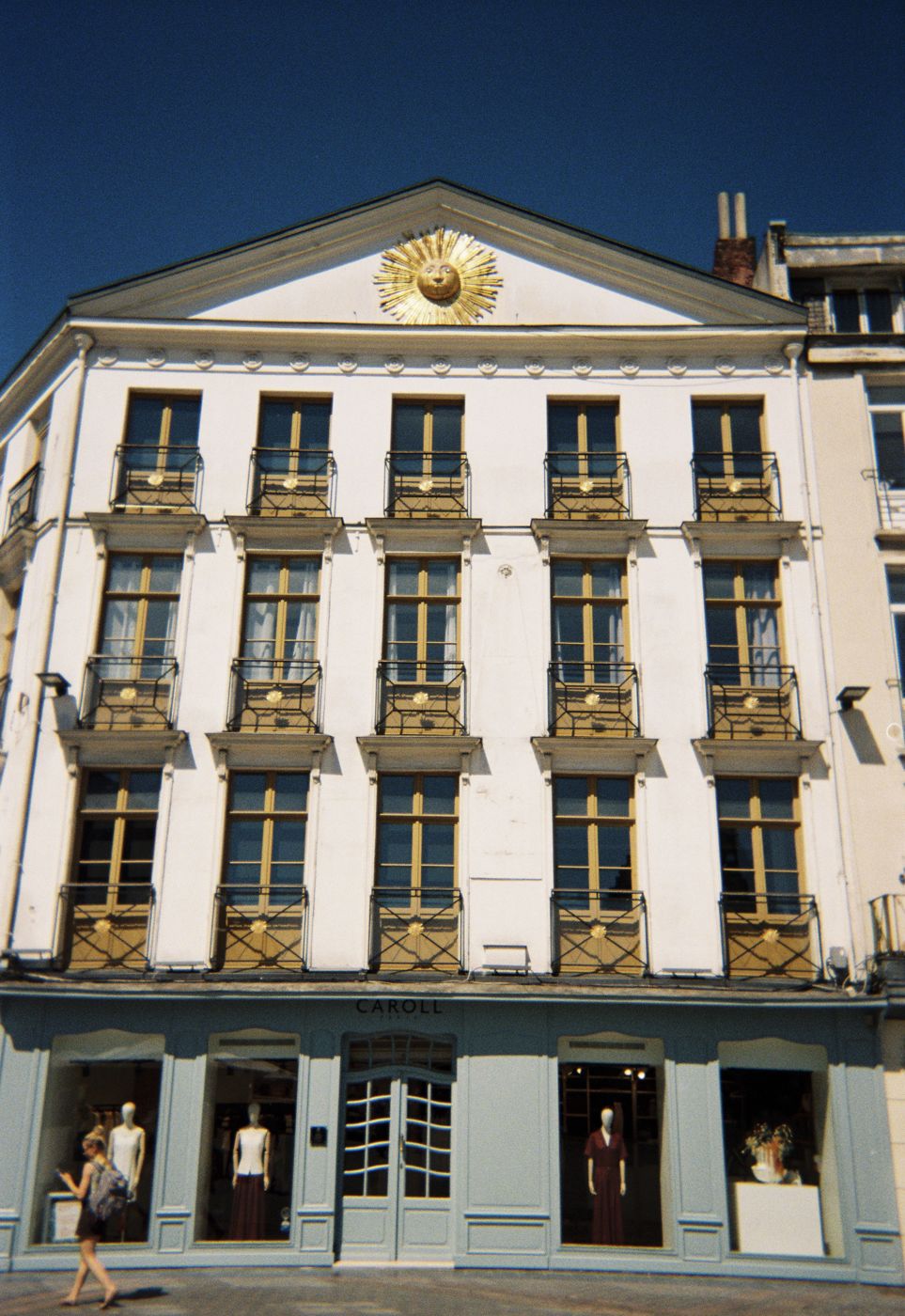The white building with the gold sun on its pediment, in full sun, on film
