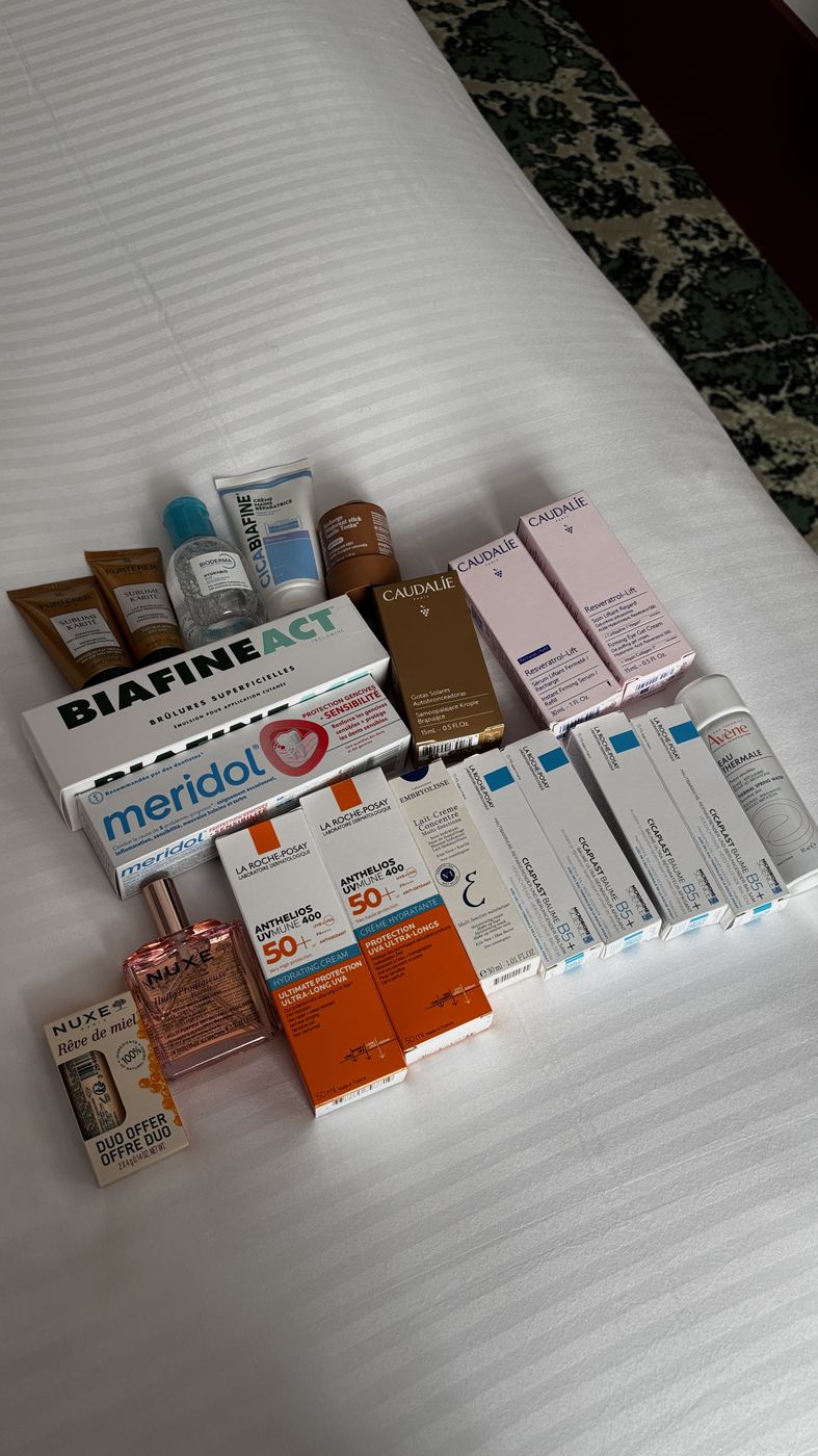 French pharmacy skincare haul laid out on a hotel bed